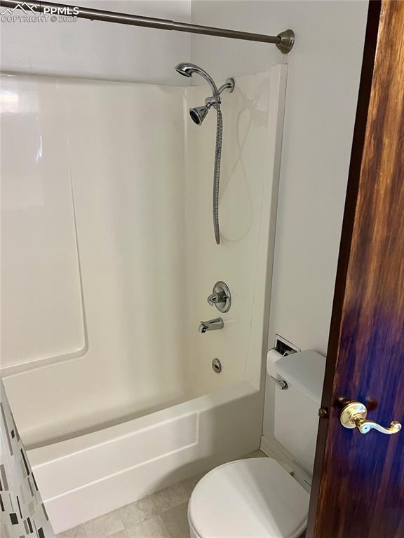 bathroom featuring tile patterned floors, toilet, and shower / tub combo