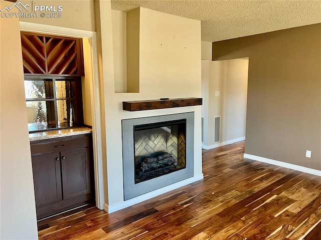 unfurnished living room with dark hardwood / wood-style flooring and a textured ceiling