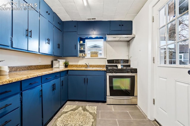 kitchen with blue cabinets, gas stove, sink, and light stone counters