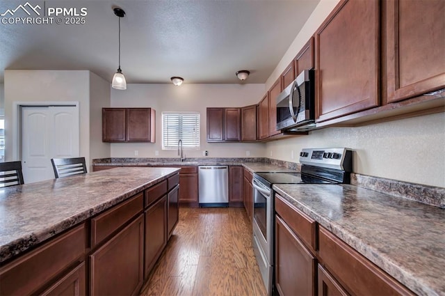 kitchen with hanging light fixtures, appliances with stainless steel finishes, sink, and dark hardwood / wood-style floors