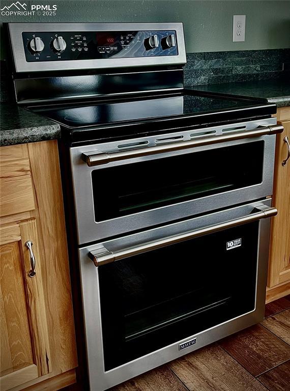 interior details featuring light brown cabinetry, multiple ovens, and dark wood-type flooring