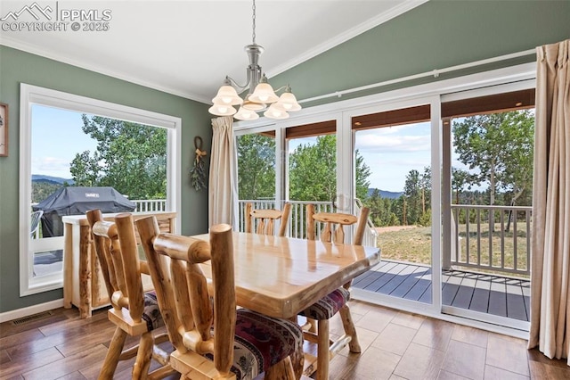 dining area with an inviting chandelier, crown molding, vaulted ceiling, and hardwood / wood-style flooring