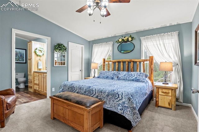 carpeted bedroom with lofted ceiling, ensuite bath, ornamental molding, and ceiling fan