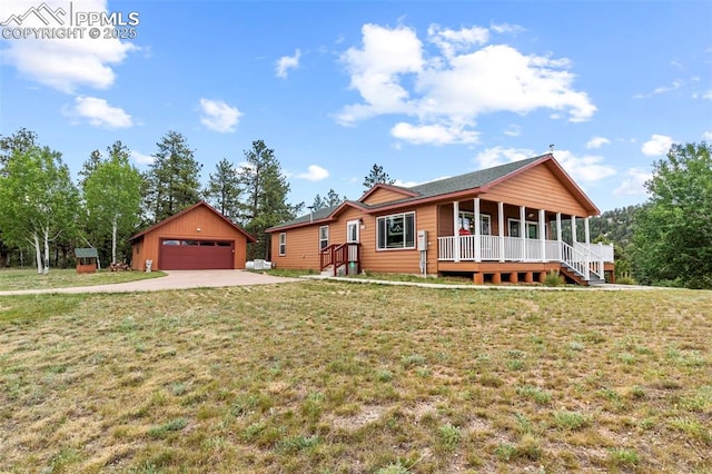 view of front of home with an outbuilding, a garage, covered porch, and a front yard