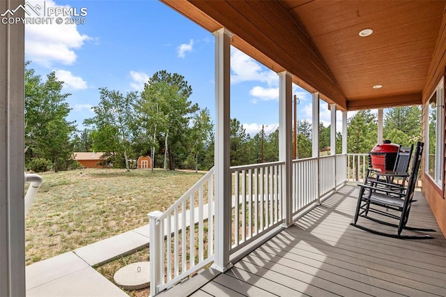 wooden terrace with a porch and a yard