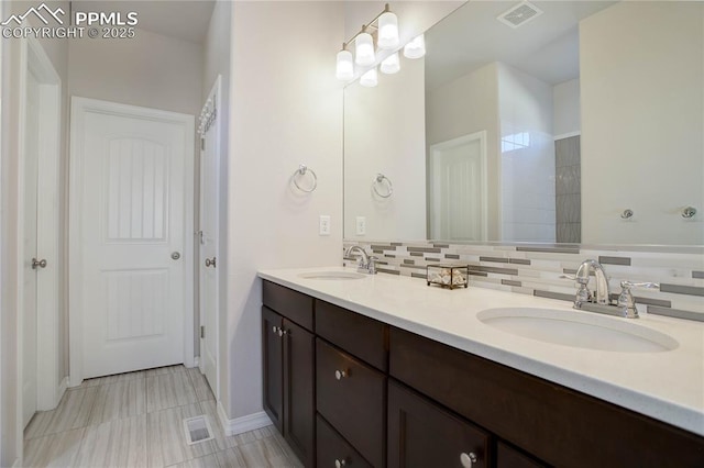 bathroom with visible vents, a sink, decorative backsplash, and double vanity