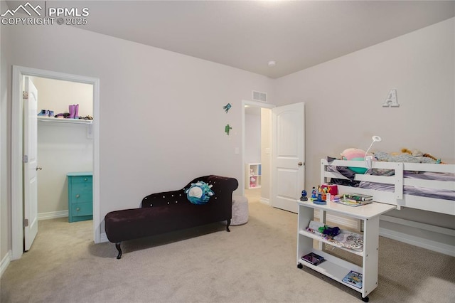 carpeted bedroom with a spacious closet, visible vents, and baseboards