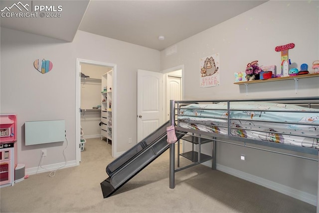 bedroom with a closet, carpet flooring, a spacious closet, and baseboards