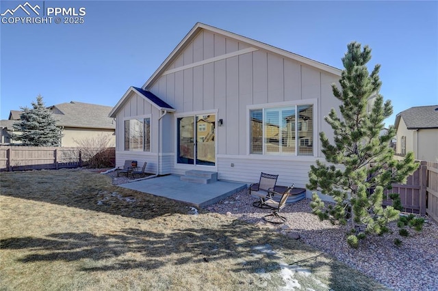 rear view of house with board and batten siding, entry steps, a patio area, and fence