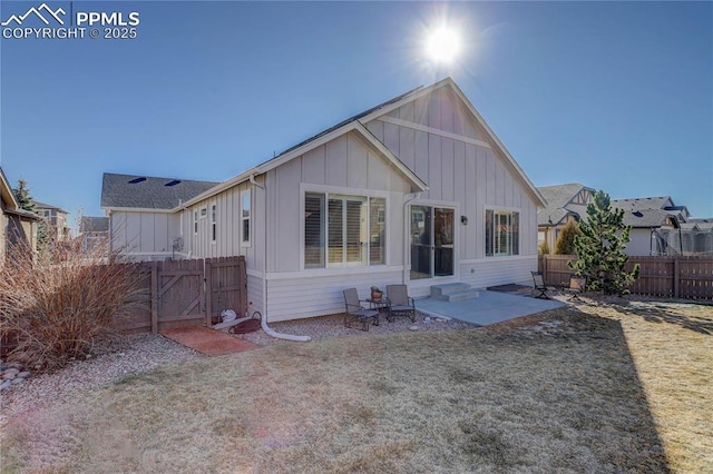 rear view of house with entry steps, fence, a yard, a patio area, and board and batten siding