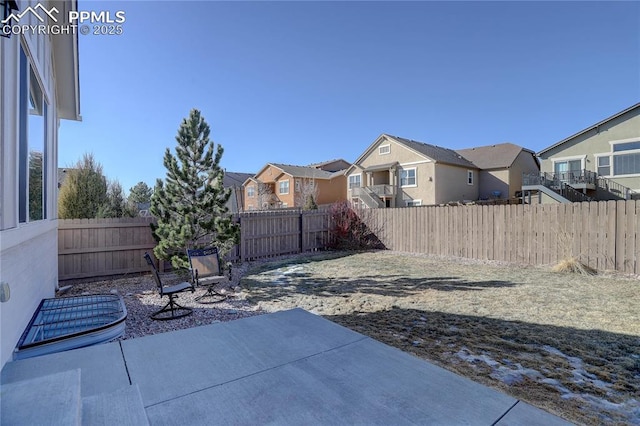 view of yard with a patio area, a fenced backyard, and a residential view