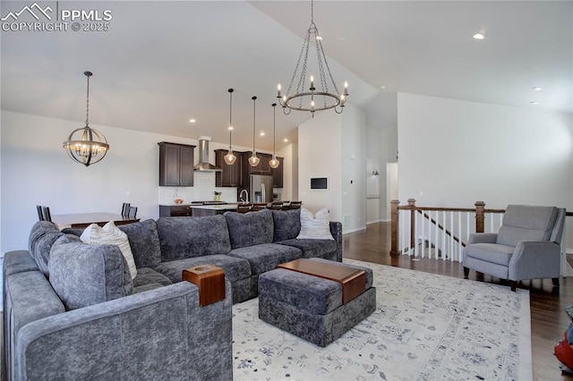 living room with a notable chandelier, high vaulted ceiling, wood finished floors, and recessed lighting