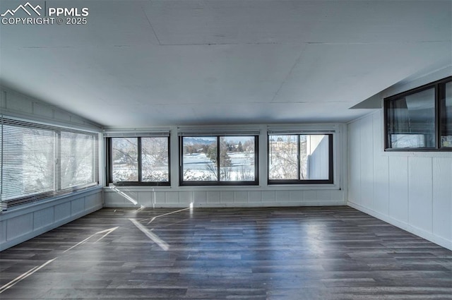 empty room with dark wood-type flooring, lofted ceiling, and a wealth of natural light