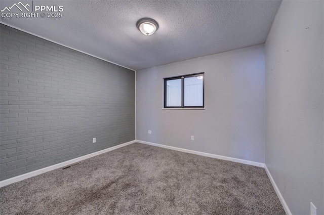 unfurnished room with brick wall, carpet flooring, and a textured ceiling