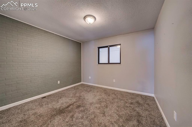 empty room featuring brick wall, carpet flooring, and a textured ceiling