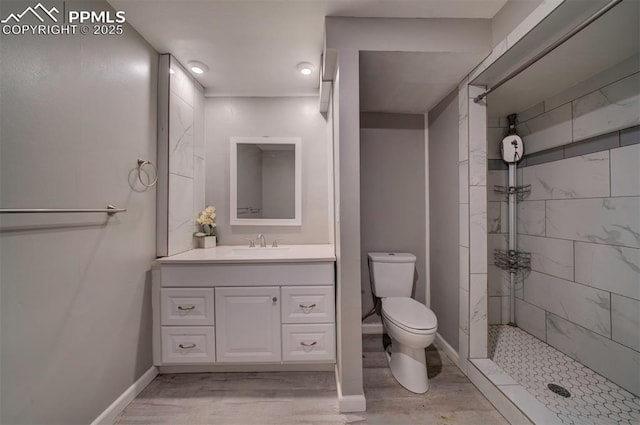 bathroom featuring vanity, hardwood / wood-style flooring, toilet, and tiled shower