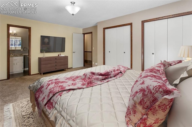 carpeted bedroom featuring ensuite bathroom and two closets