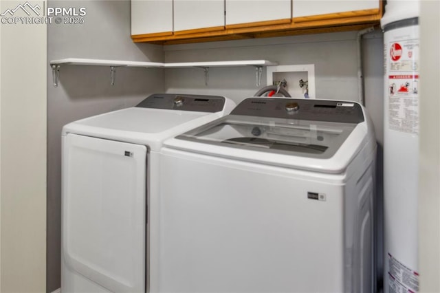 clothes washing area featuring washer and clothes dryer, gas water heater, and cabinets