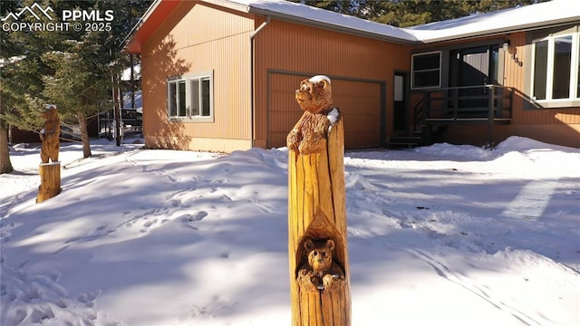 view of snow covered exterior featuring a garage