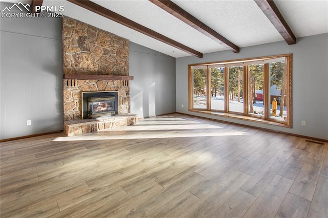 unfurnished living room featuring vaulted ceiling with beams, a textured ceiling, a fireplace, and light wood-type flooring