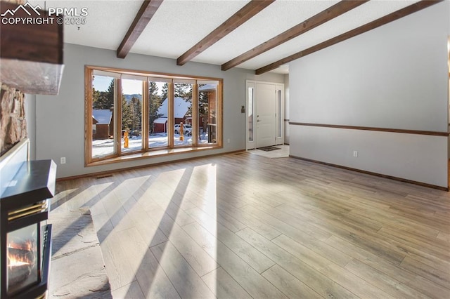 unfurnished living room featuring beam ceiling and light wood-type flooring