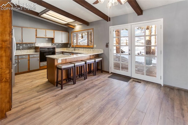 kitchen with tasteful backsplash, black appliances, kitchen peninsula, a kitchen bar, and french doors