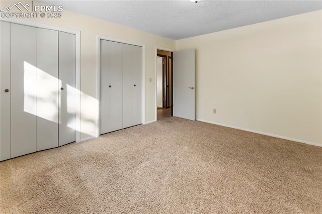 unfurnished bedroom with two closets and carpet floors