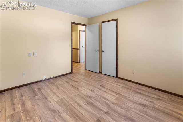 unfurnished room with a textured ceiling and light hardwood / wood-style floors