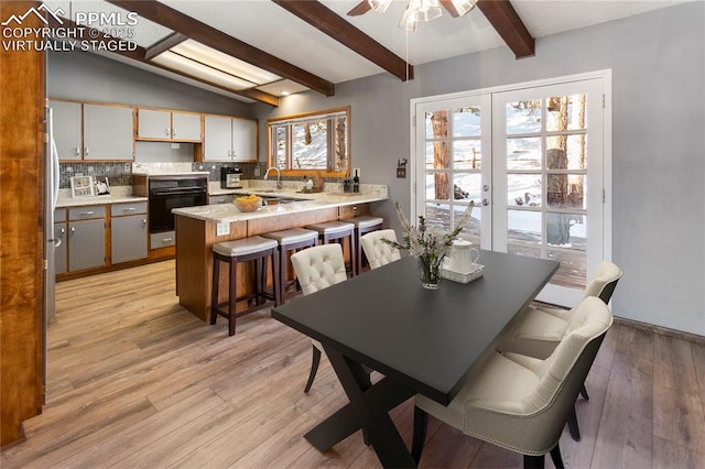 dining space with lofted ceiling with beams, sink, ceiling fan, light hardwood / wood-style floors, and french doors