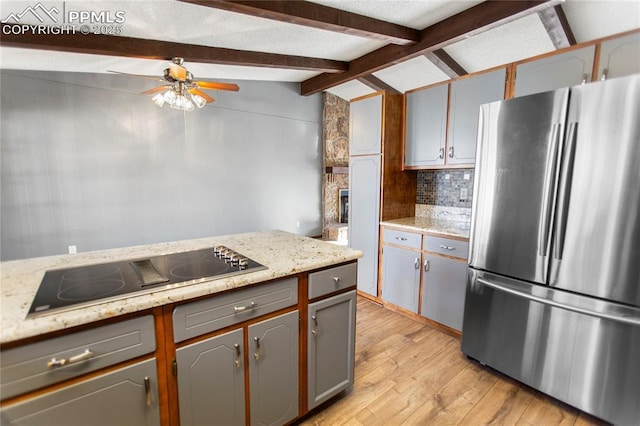 kitchen featuring vaulted ceiling with beams, stainless steel refrigerator, black electric cooktop, gray cabinets, and decorative backsplash