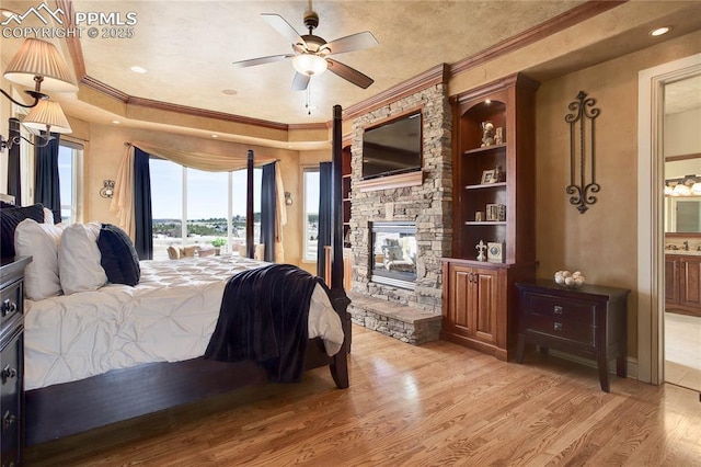 bedroom featuring a fireplace, access to outside, light hardwood / wood-style floors, crown molding, and ensuite bath