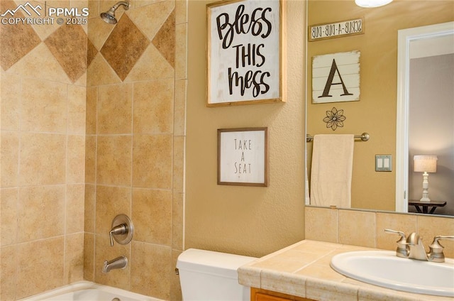 full bathroom featuring tiled shower / bath, vanity, and toilet