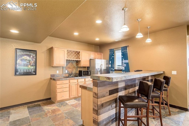 kitchen featuring sink, decorative light fixtures, light brown cabinets, appliances with stainless steel finishes, and kitchen peninsula