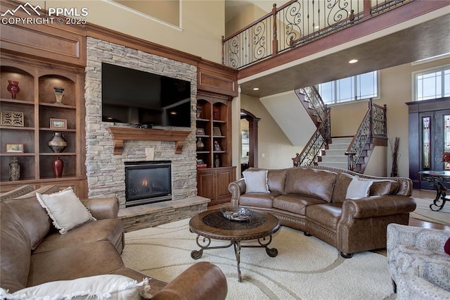 living room featuring ornate columns, a fireplace, built in features, and a high ceiling