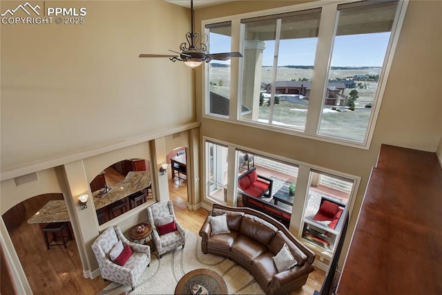 sitting room featuring a towering ceiling, hardwood / wood-style floors, and ceiling fan