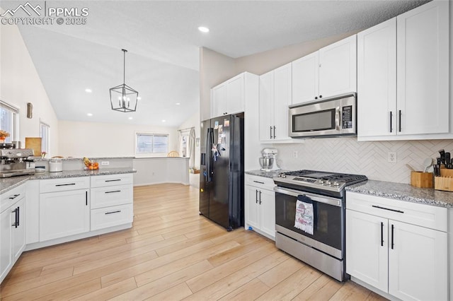 kitchen with light stone counters, vaulted ceiling, stainless steel appliances, and white cabinets