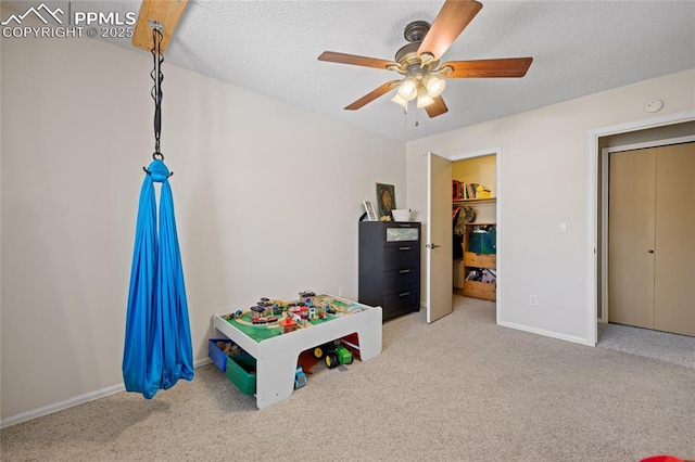 rec room with light carpet, ceiling fan, and a textured ceiling