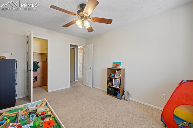 recreation room featuring light carpet, a textured ceiling, and ceiling fan