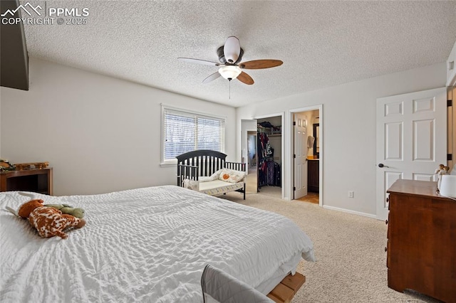 carpeted bedroom with ceiling fan, ensuite bathroom, a textured ceiling, a spacious closet, and a closet