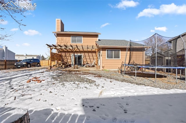 snow covered rear of property featuring a trampoline and a pergola