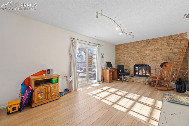 interior space with a stone fireplace, a textured ceiling, and light hardwood / wood-style floors