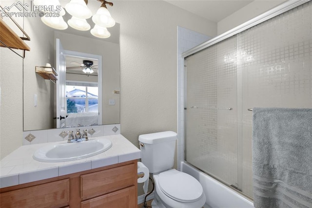 full bathroom featuring ceiling fan, vanity, toilet, and combined bath / shower with glass door