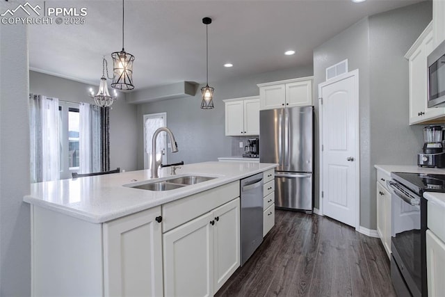 kitchen with a sink, dark wood-style floors, stainless steel appliances, white cabinetry, and an island with sink