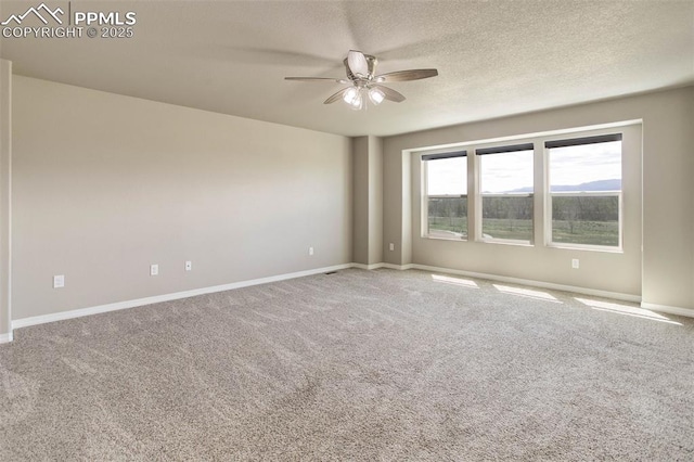 carpeted spare room with baseboards, a ceiling fan, and a textured ceiling