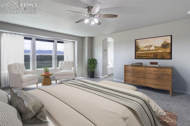 bedroom with carpet floors, arched walkways, baseboards, and ceiling fan