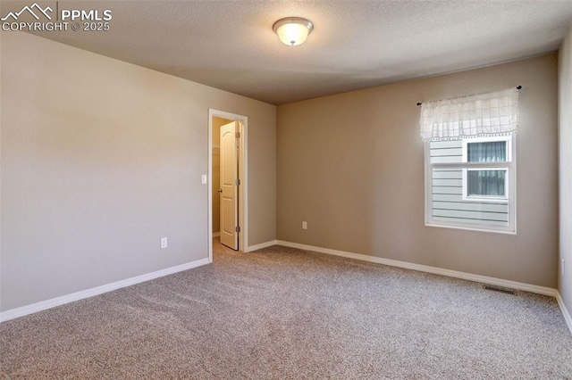 empty room featuring baseboards, carpet flooring, a textured ceiling, and visible vents