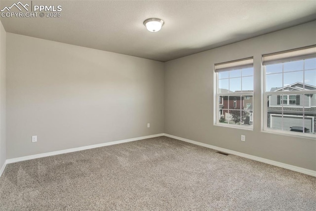 carpeted spare room with visible vents and baseboards