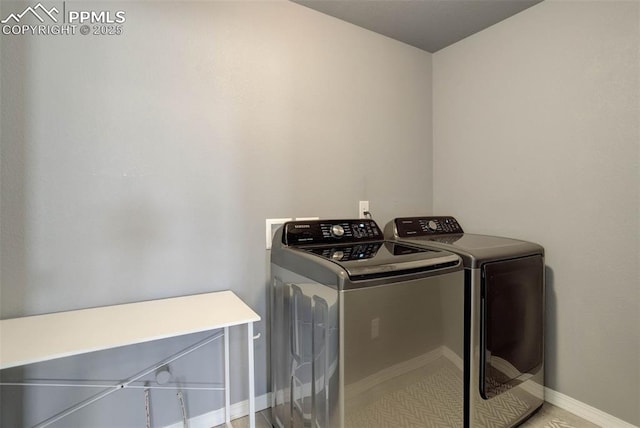 clothes washing area featuring baseboards, laundry area, and washing machine and dryer