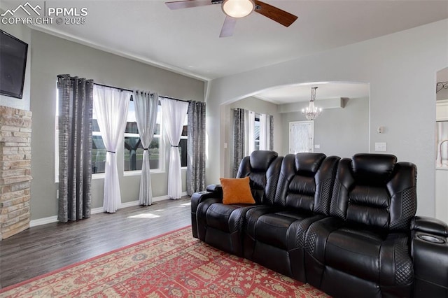 living area with arched walkways, baseboards, ceiling fan with notable chandelier, and wood finished floors