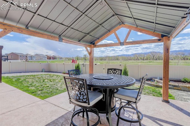 view of patio / terrace with outdoor dining space, a gazebo, a mountain view, and a fenced backyard